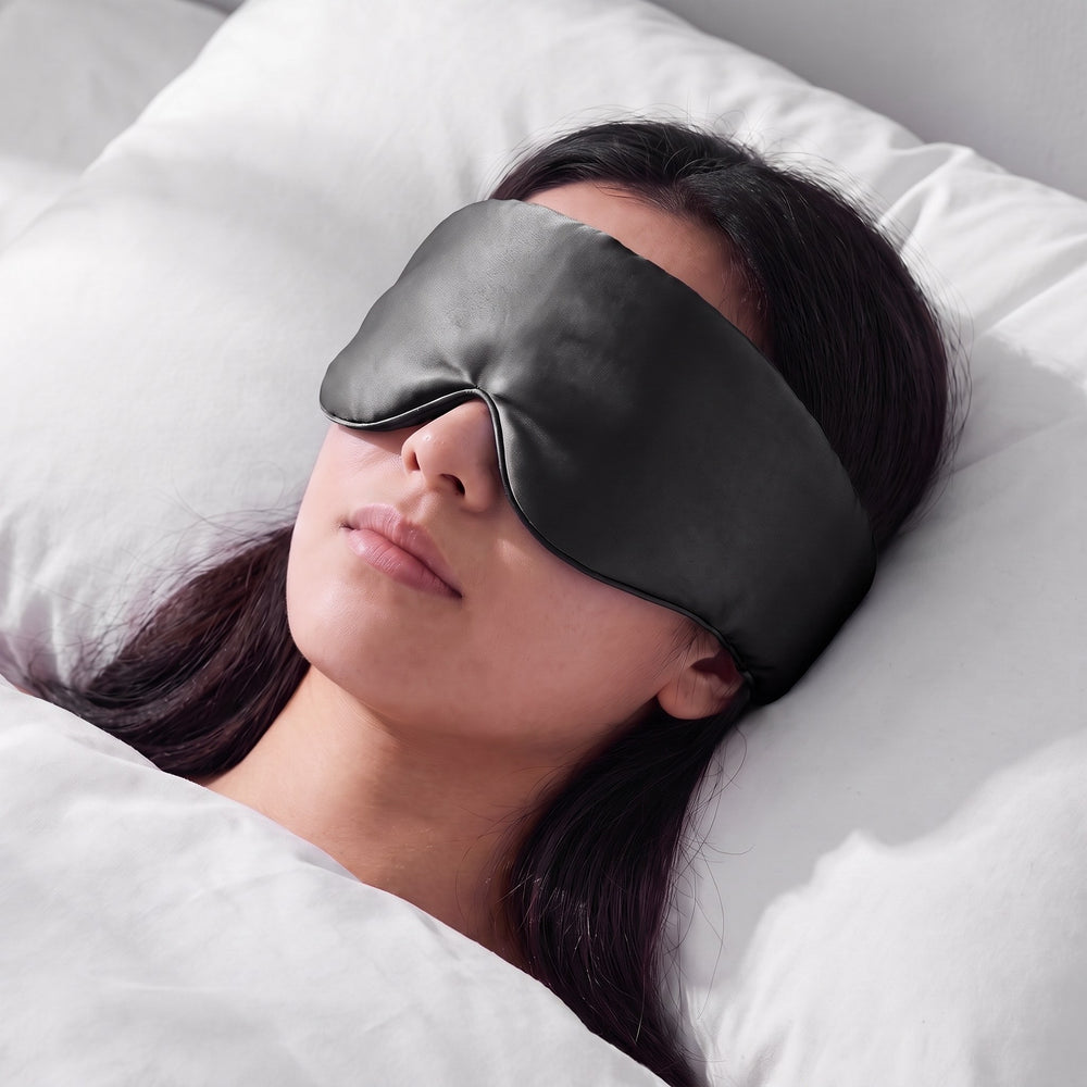 A woman asleep wearing the Vespré Silk Sleep Mask in Black