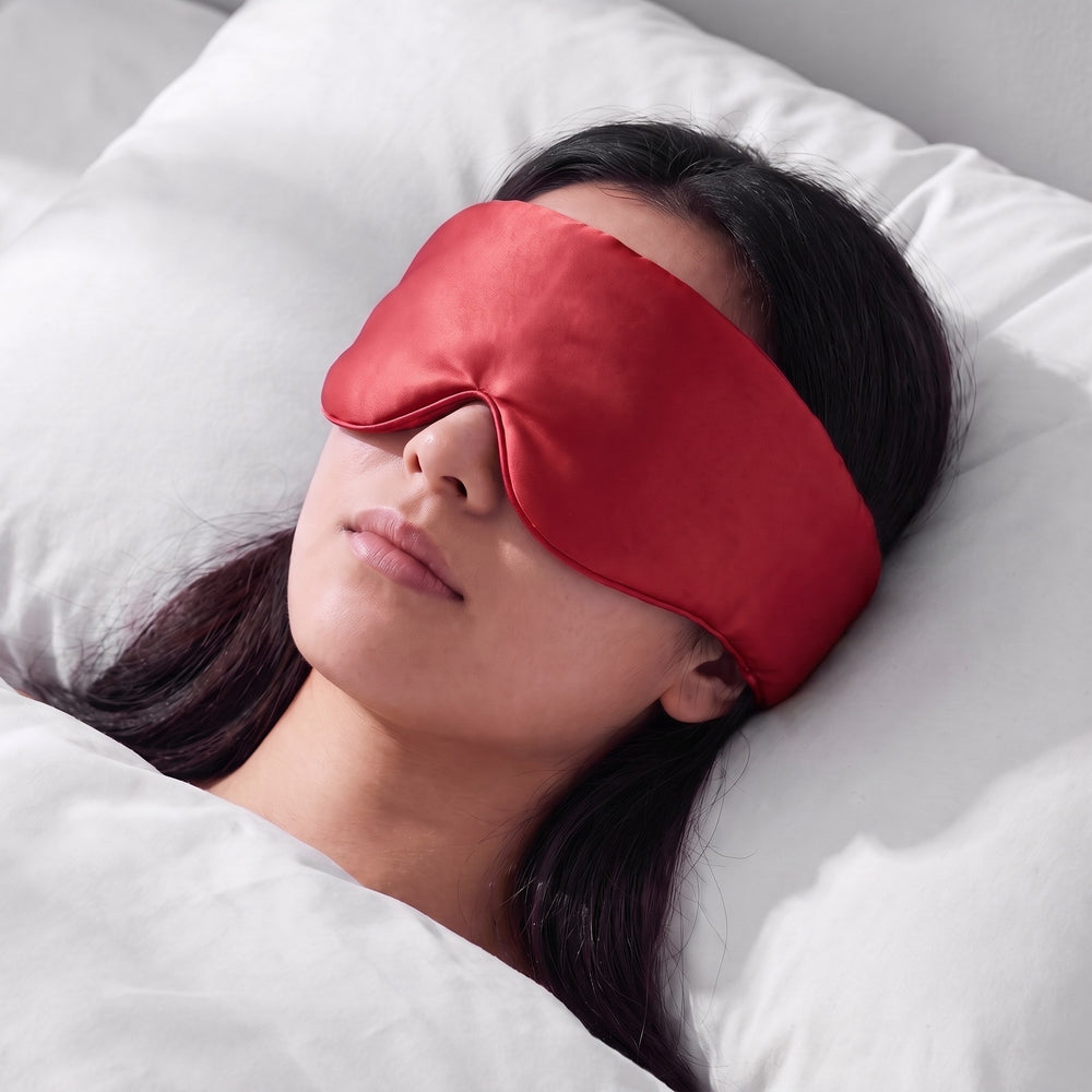 A woman asleep wearing the Vespré Silk Sleep Mask in Red