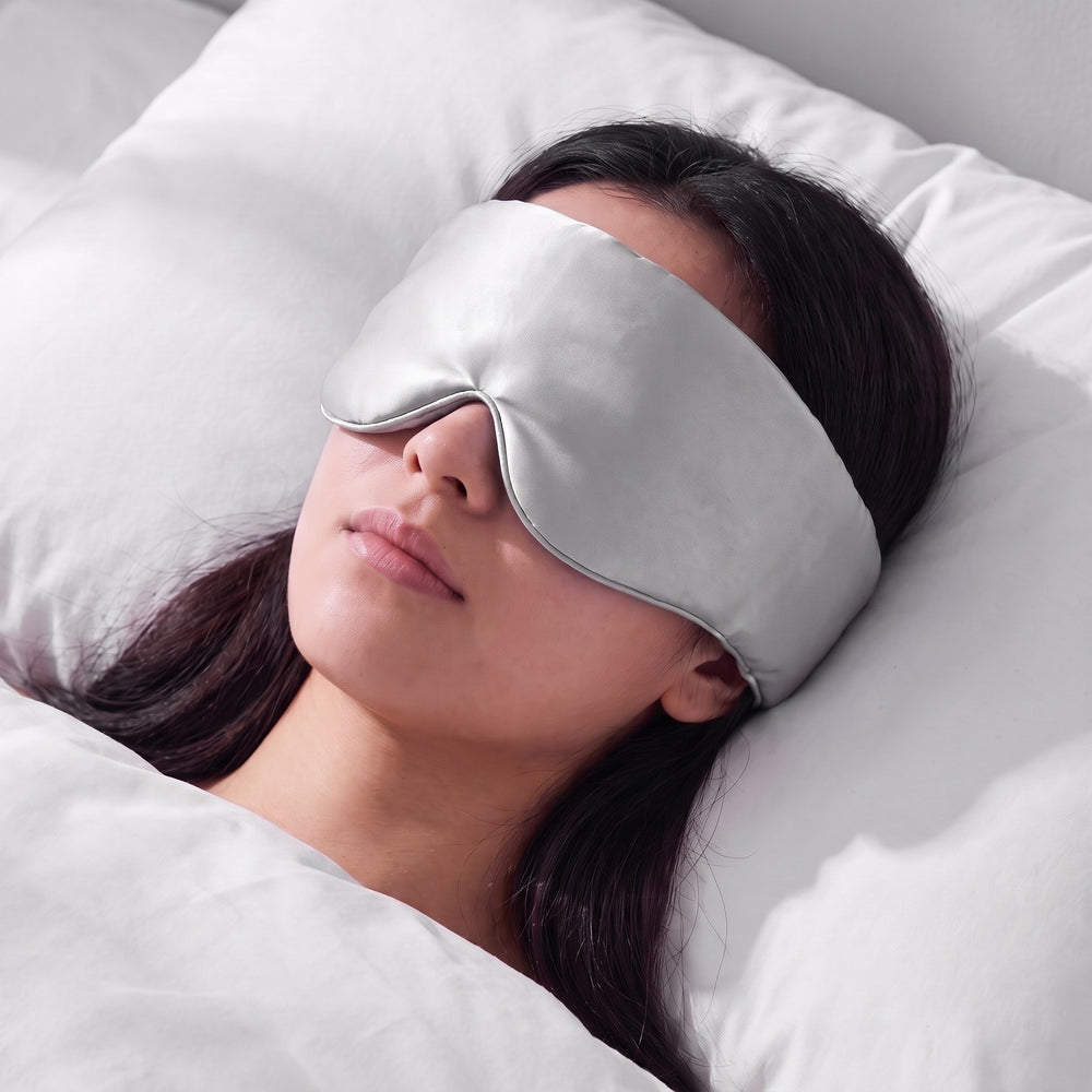 A woman asleep wearing the Vespré Silk Sleep Mask in Silver