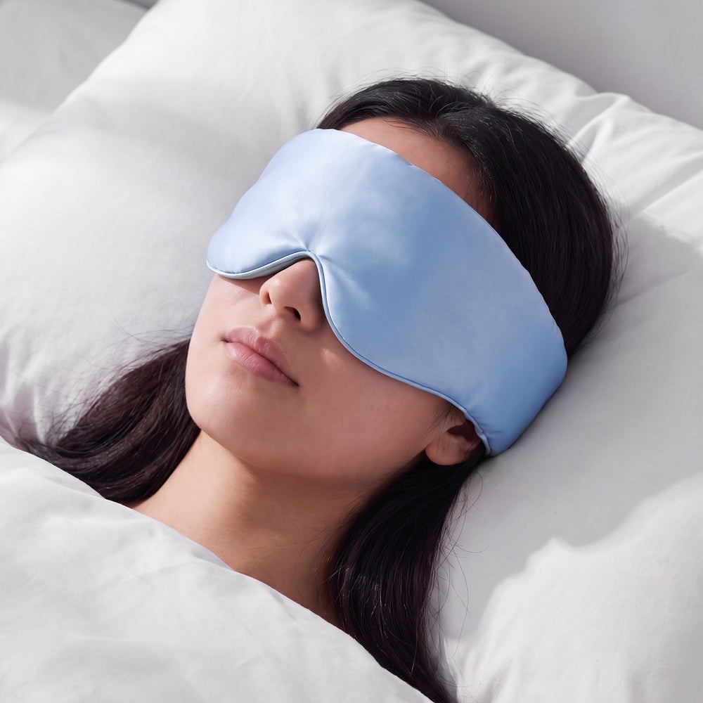 A woman asleep wearing the Vespré Silk Sleep Mask in Sky Blue