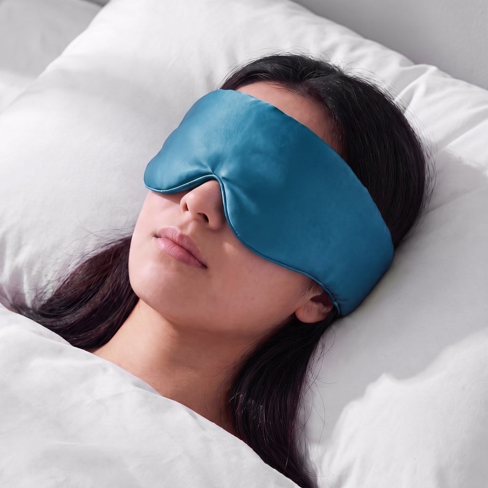 A woman asleep wearing the Vespré Silk Sleep Mask in Teal