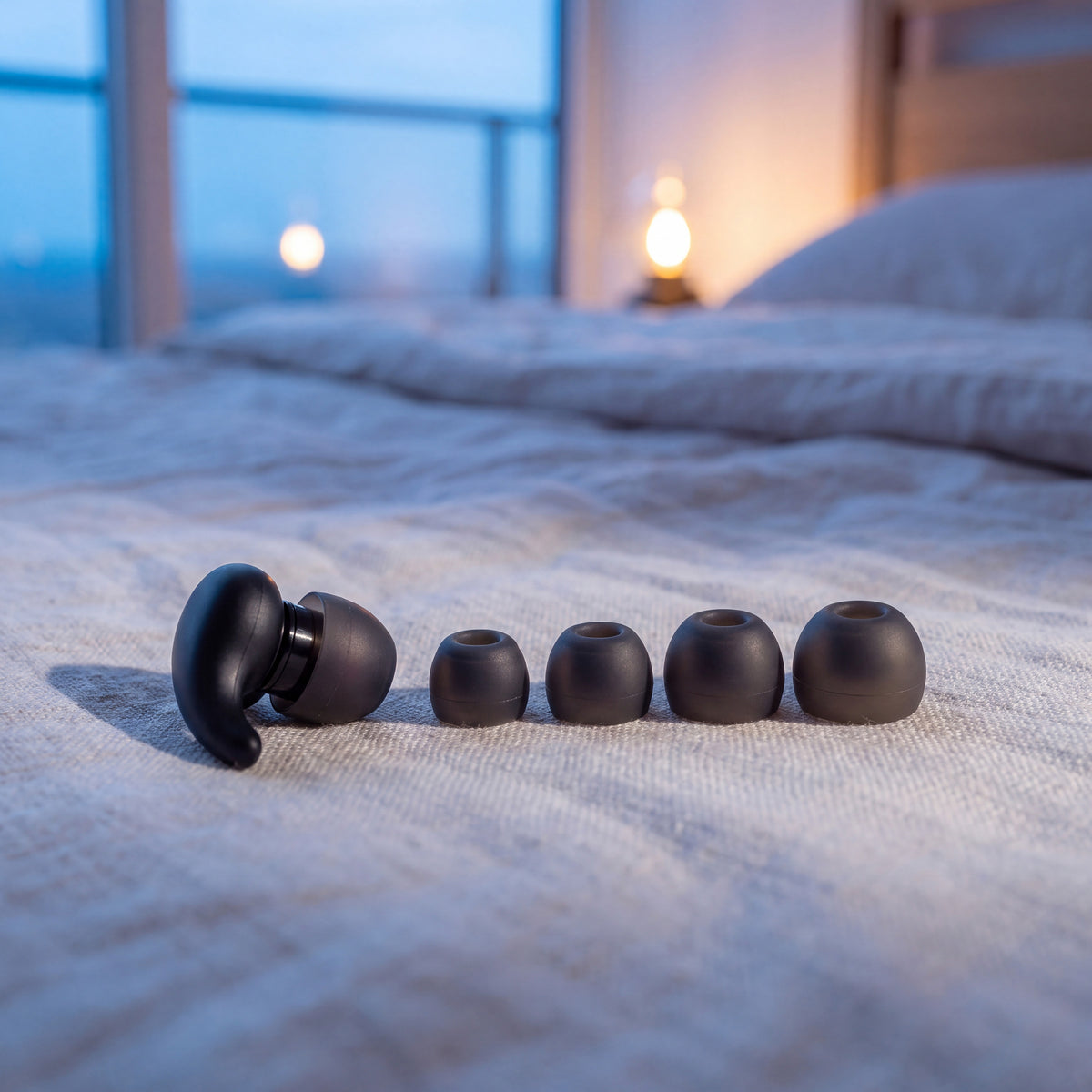 A Vespré Wing earplug beside four spare tips from smallest to largest