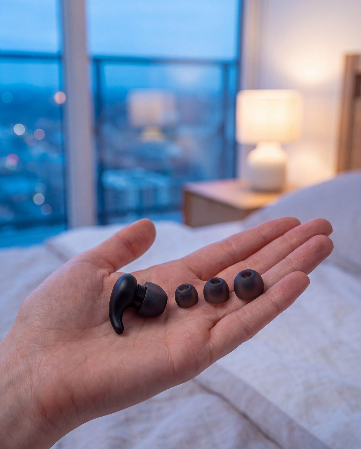 Fingertips holding a soft silicone ear tip beside the ear