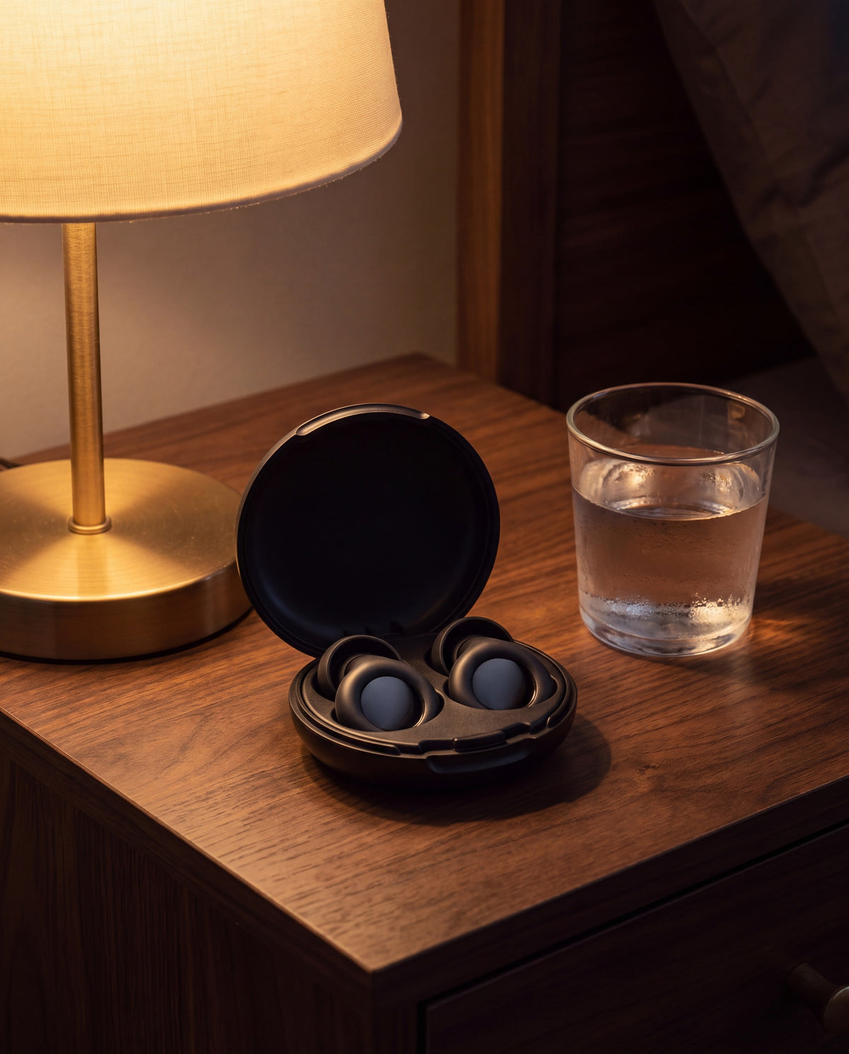 Vespré Deep case open on a nightstand beside a lamp and a glass of water