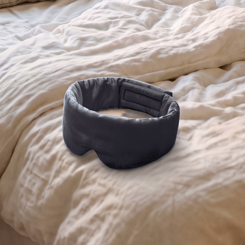 The Vespré Silk Sleep Mask in Black resting on a linen bed in morning light