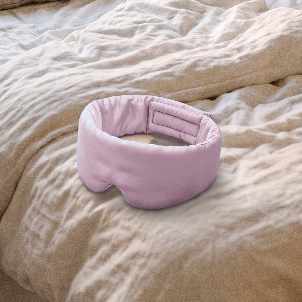 The Vespré Silk Sleep Mask in Blush Pink resting on a linen bed in morning light