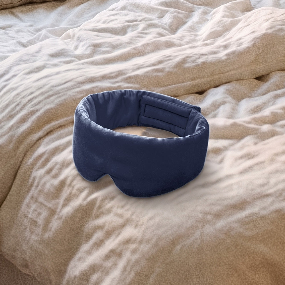 The Vespré Silk Sleep Mask in Navy resting on a linen bed in morning light