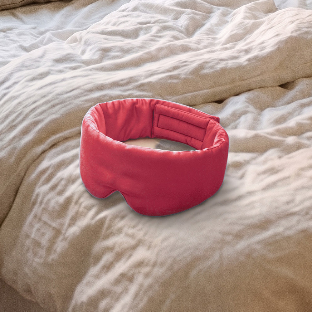The Vespré Silk Sleep Mask in Red resting on a linen bed in morning light