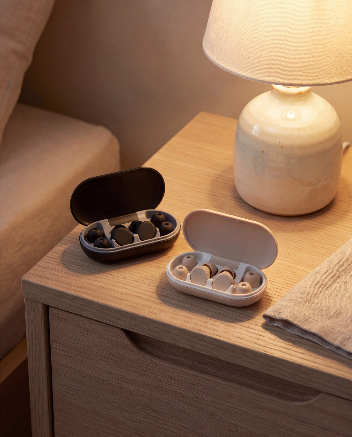 Two Vespré Rest cases open on a nightstand, black and ivory