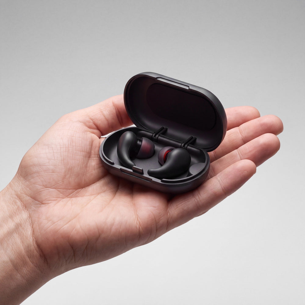 Vespré Wing in Matte Black, open case with both earplugs held in a hand for scale